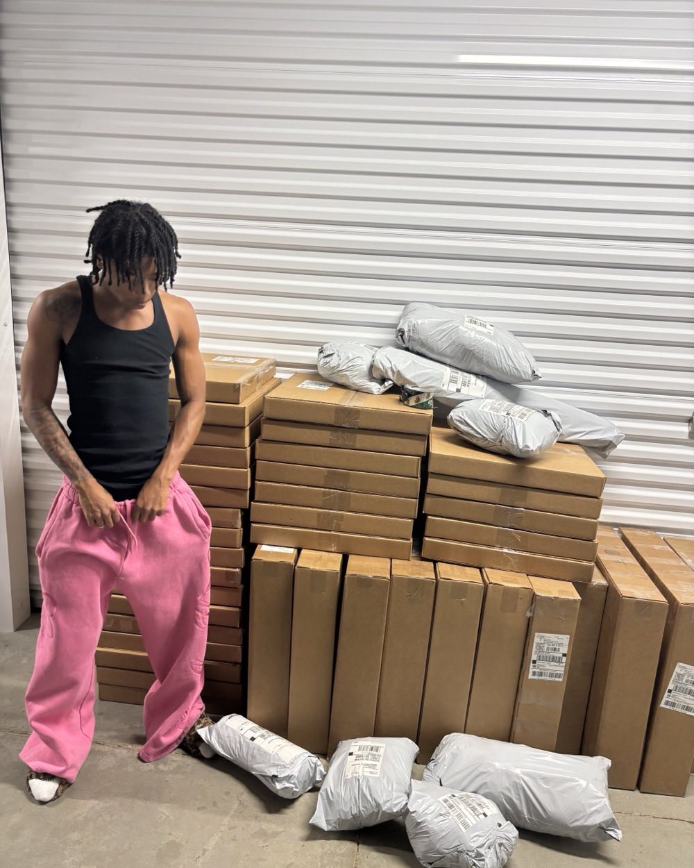 Dez, founder of Crib Essentials, standing beside a wall of packed orders ready to ship